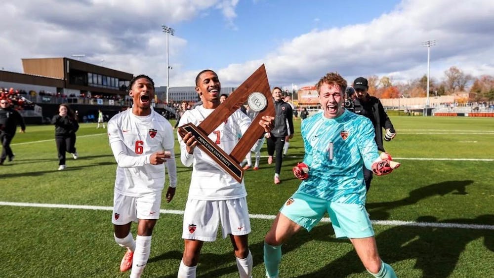 Three soccer players celebrating with trophy.