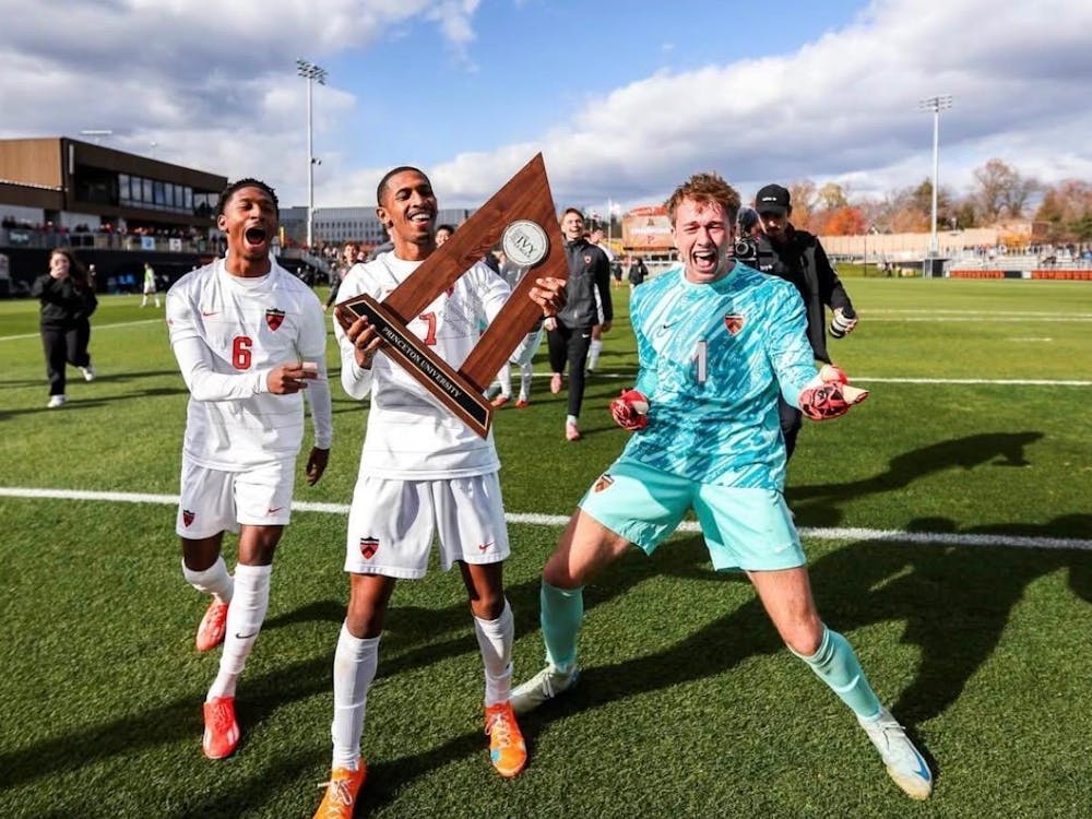 Three soccer players celebrating with trophy.