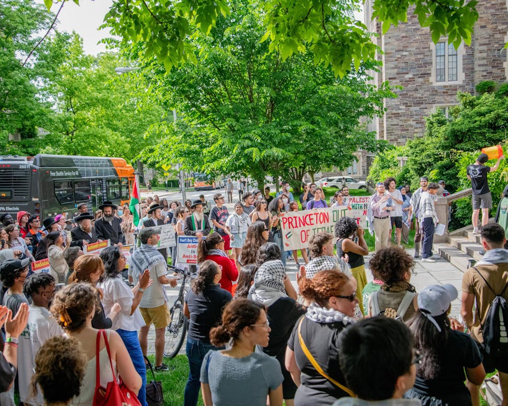 A crowd is gathered in front of a building, and many are holding signs. One sign reads “Princeton out of Israel.” Other hold signs supporting Israel. 