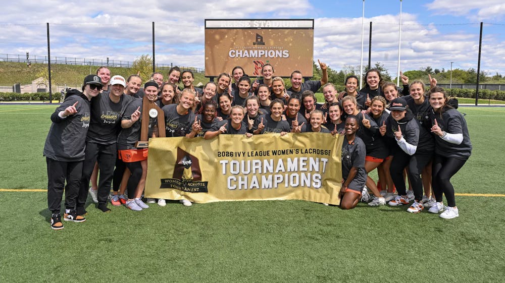 Players and staff hold up a “1” signifying first place and pose with a banner and trophy.