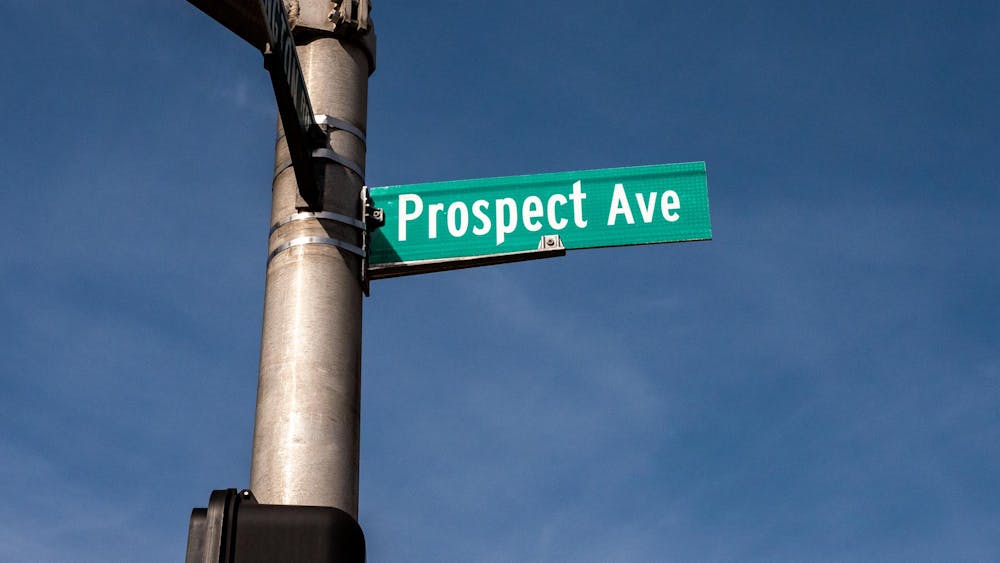 Green street sign against blue sky. The sign reads “Prospect Ave.”