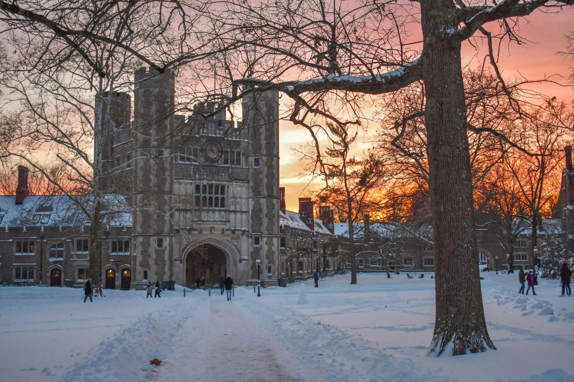 Large arched gothic building in snow-covered ground with sunset at the back.