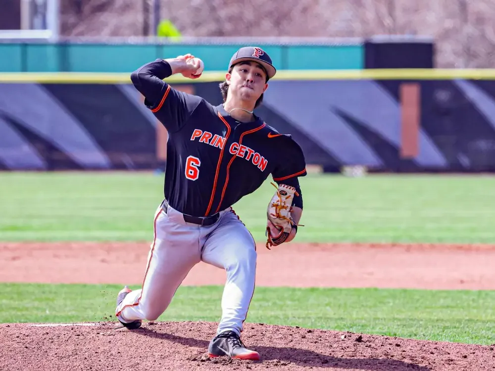 Princeton pitcher in black and orange uniform throws a pitch from the mound.