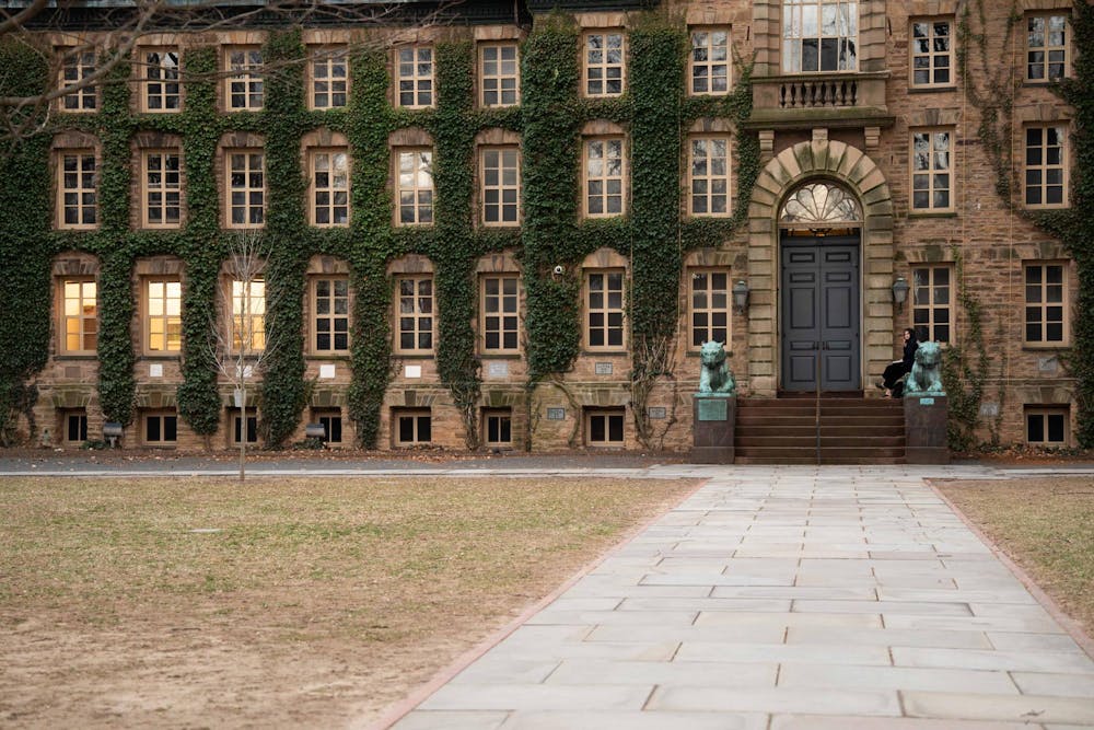 A building covered in ivy, with rows of tall windows and two bronze tiger statues flanking the main entrance steps.