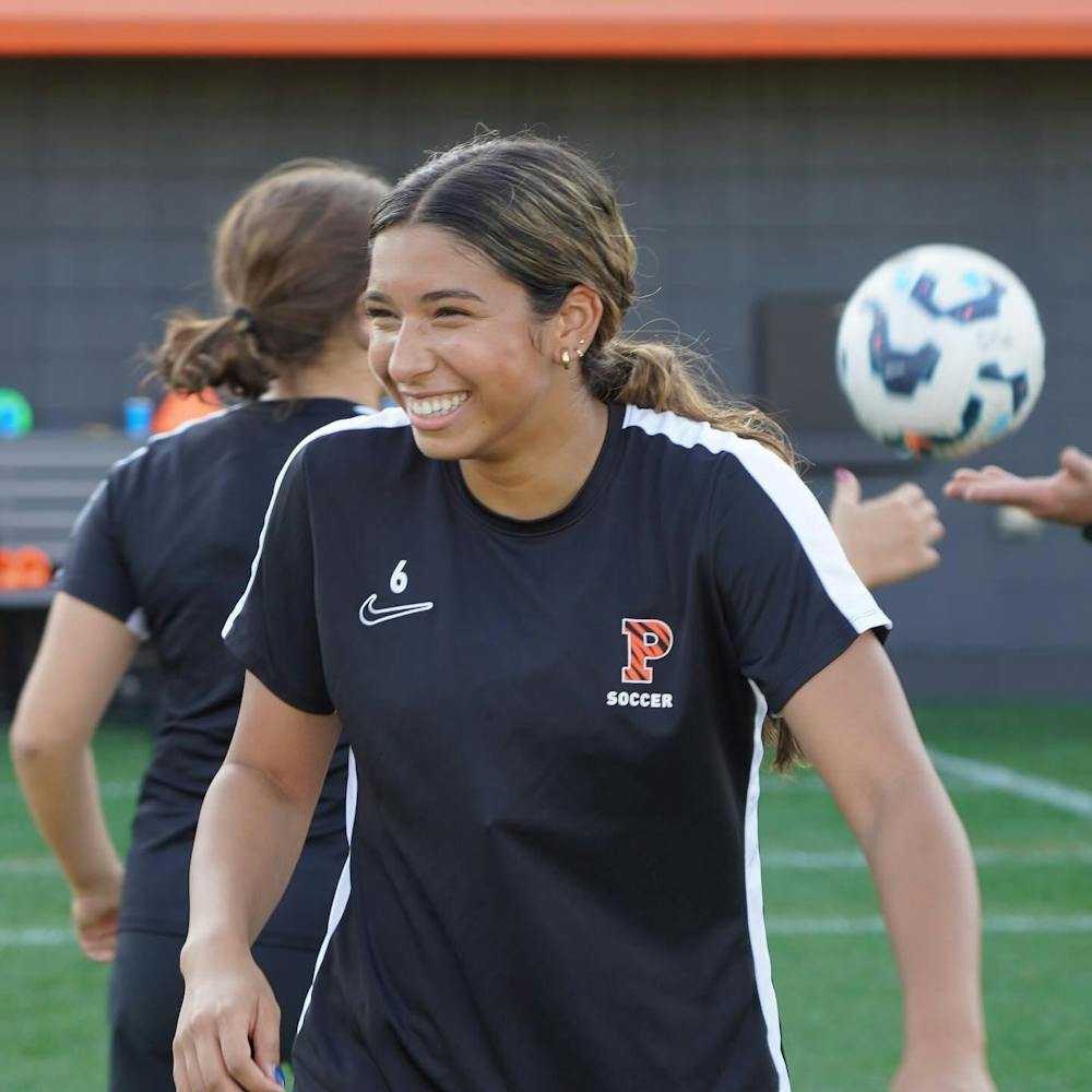 Girl wearing soccer jersey smiles away from the camera 