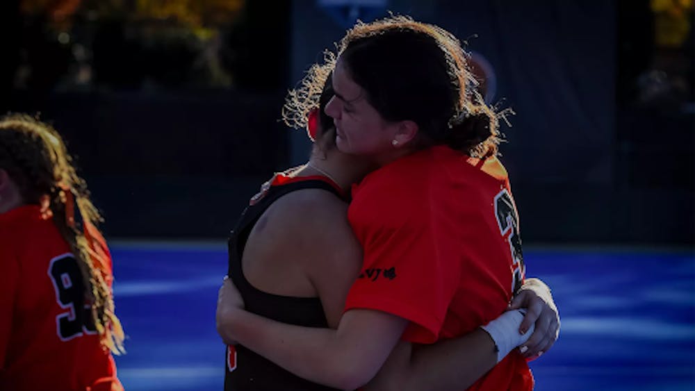 Girl in orange jersey hugs one in black jersey