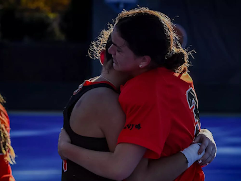 Girl in orange jersey hugs one in black jersey