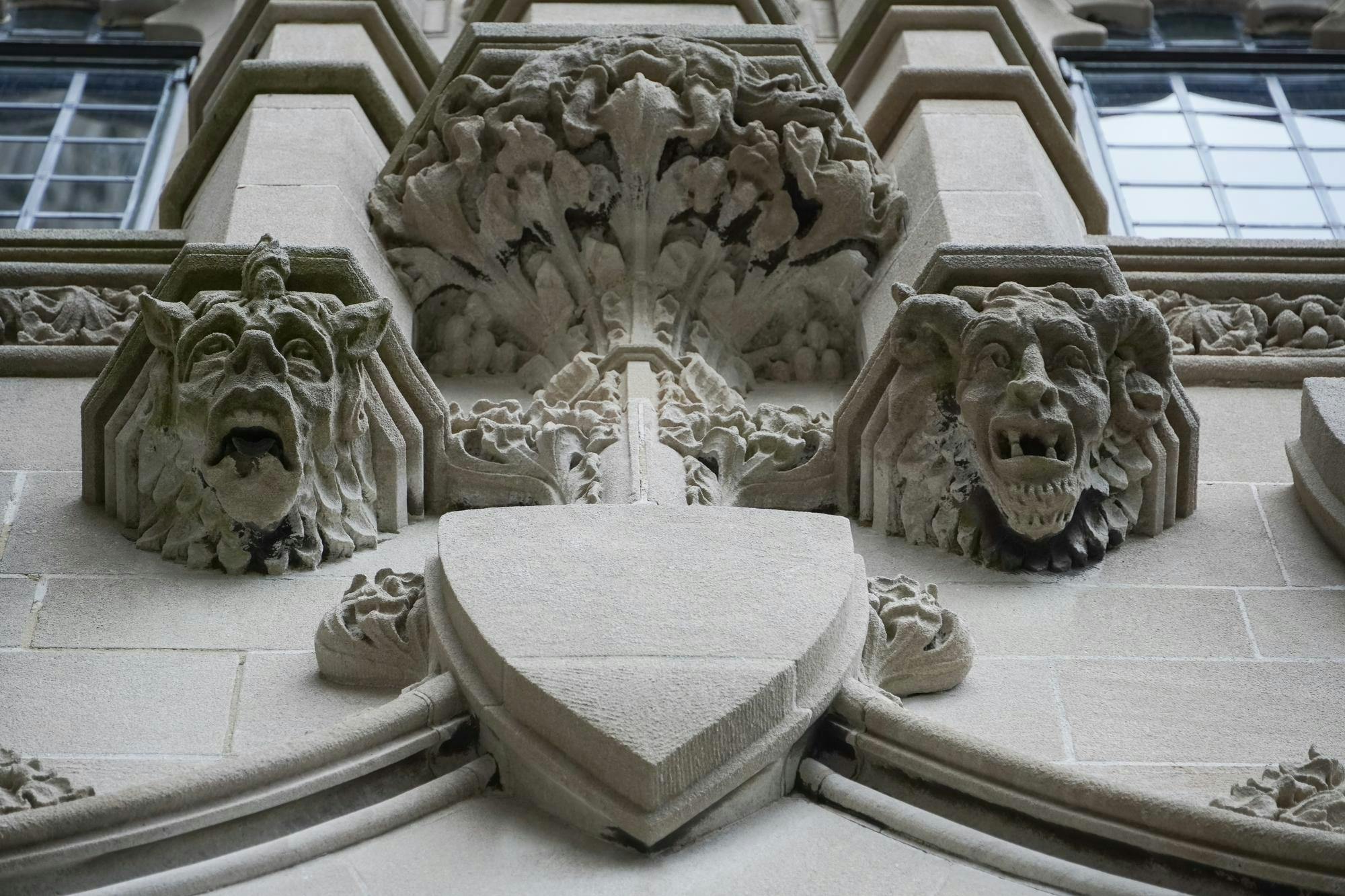 A stone gargoyle with two heads, one with a single horn in the center and one with two horns on the sides.