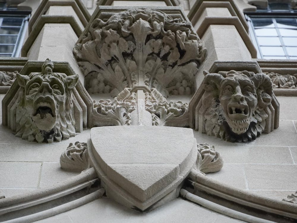 A stone gargoyle with two heads, one with a single horn in the center and one with two horns on the sides.