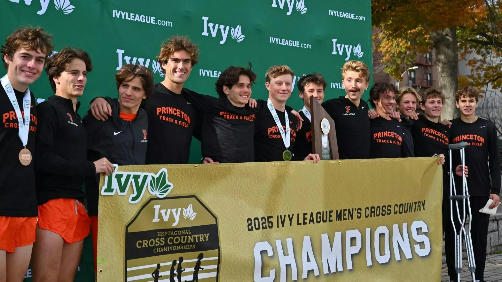 Twelve runners in black shirts smile with gold medals around their necks.