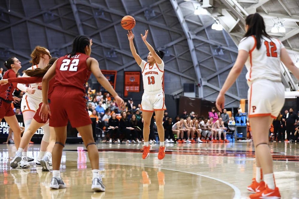 A basketball player in a white jersey shoots a three-point shot.