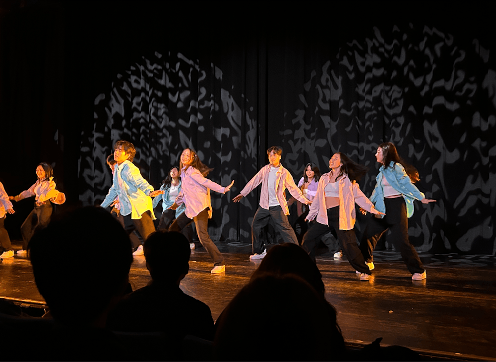 10 people on a stage dancing with matching pastel outfits.