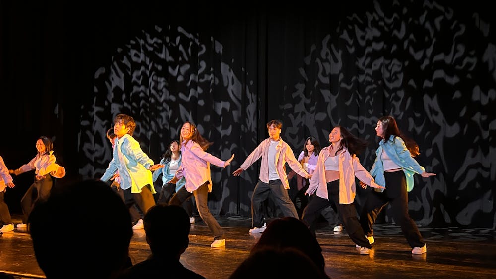 10 people on a stage dancing with matching pastel outfits.