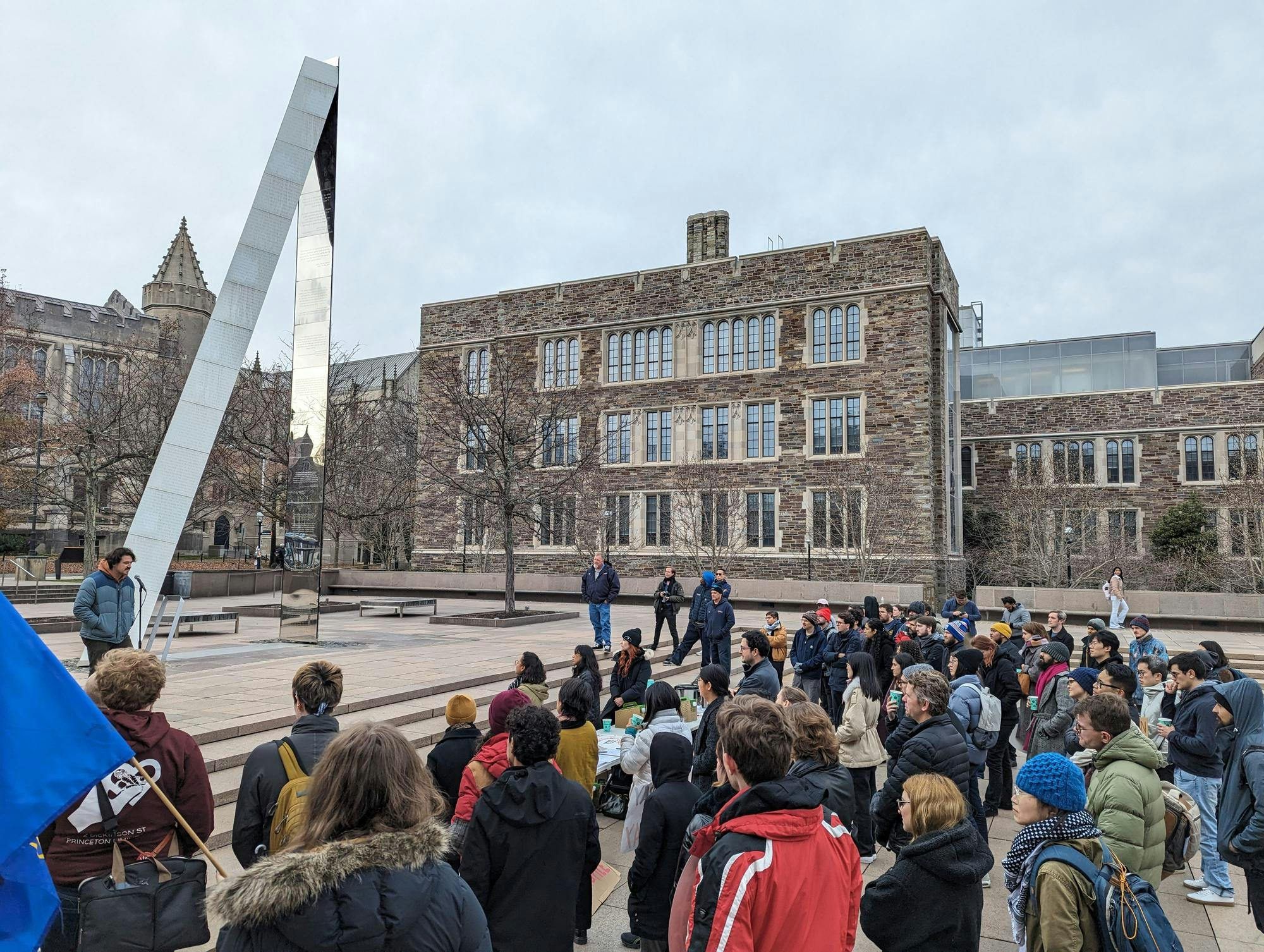 Group of adults stand in front of SPIA fountain. Large triangle monument sits in middle of fountain. 