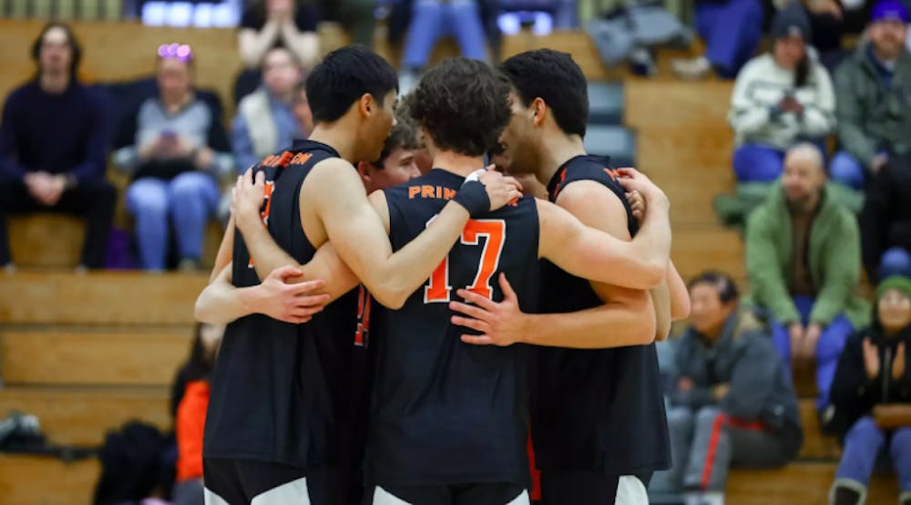 Princeton volleyball players in a group huddle.