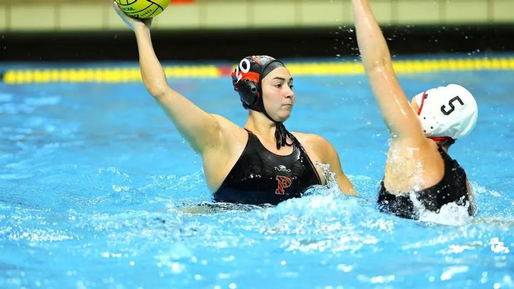 A woman in the water holding a water polo ball as a defender attempts to steal it. 