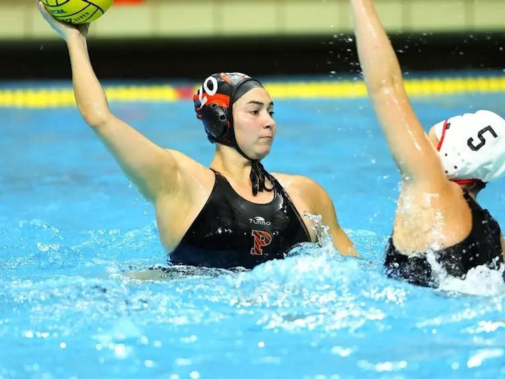 A woman in the water holding a water polo ball as a defender attempts to steal it. 