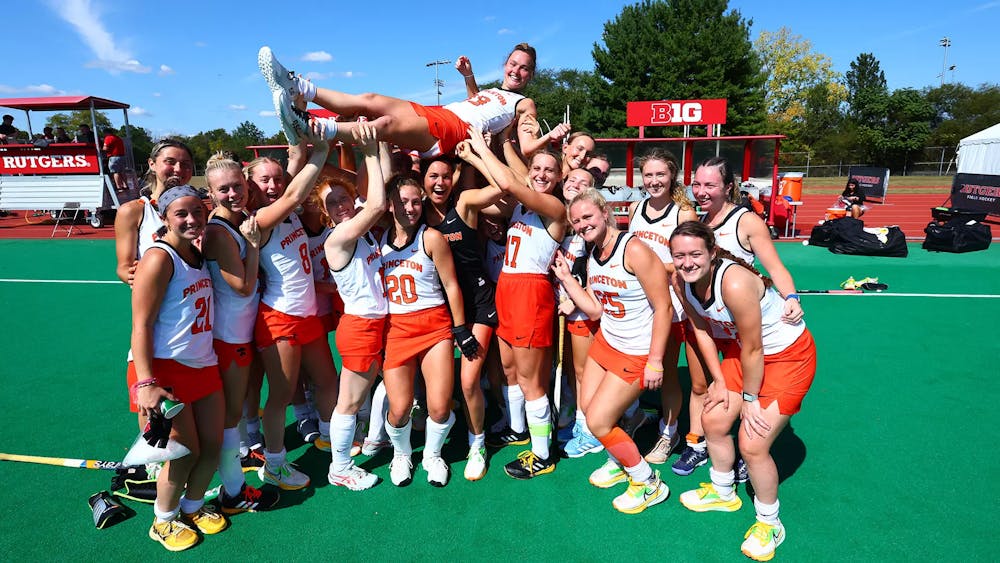 Group of Princeton field hockey players hoist teammate in celebration.