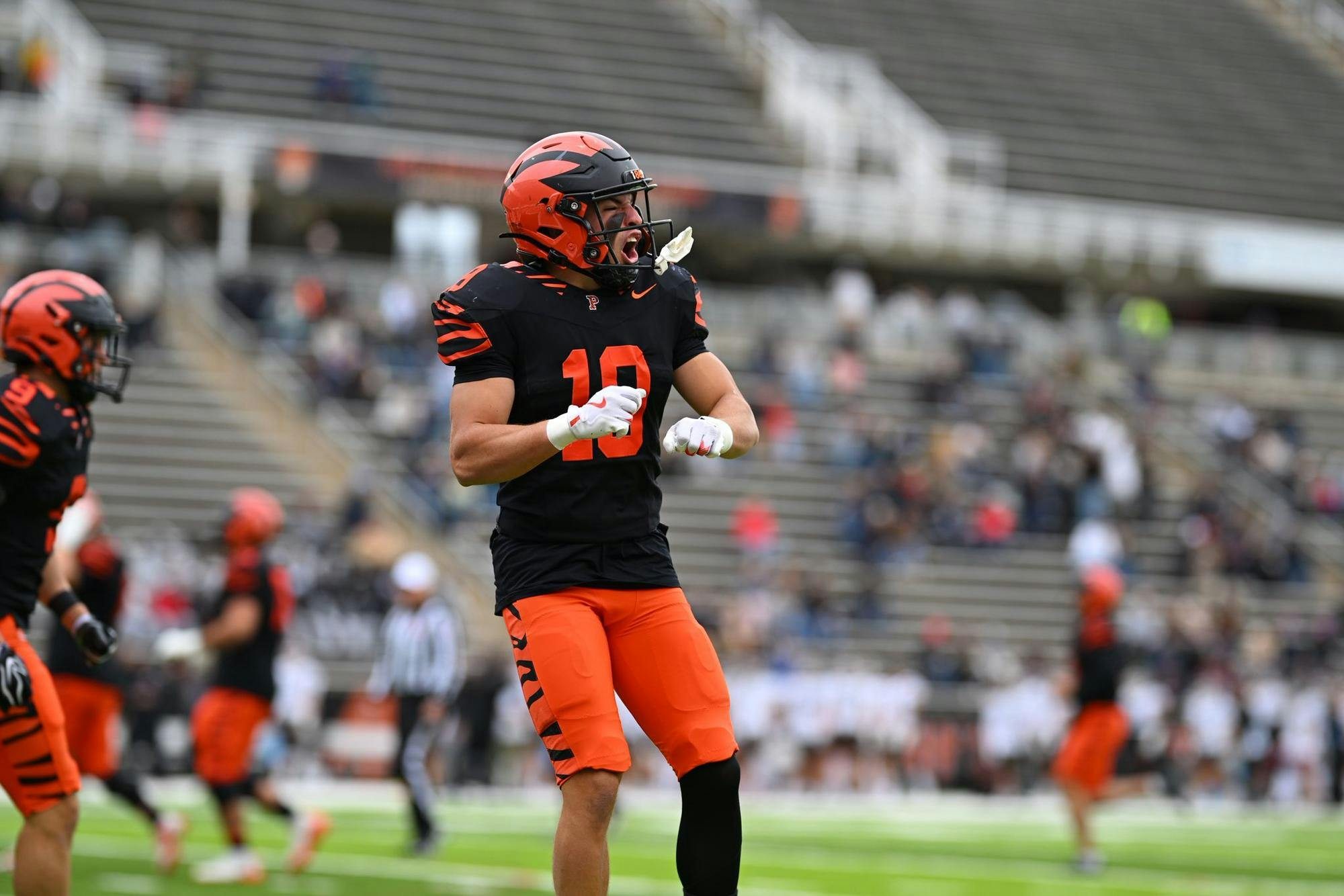 Princeton player in orange and black uniform celebrates.