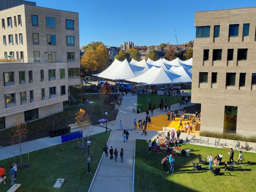 A festival is held under white tents in between the structures of Yeh College and New College West with many students walking around.