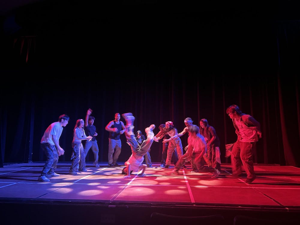 A group of dancers on stage, lit up by blue and red lights