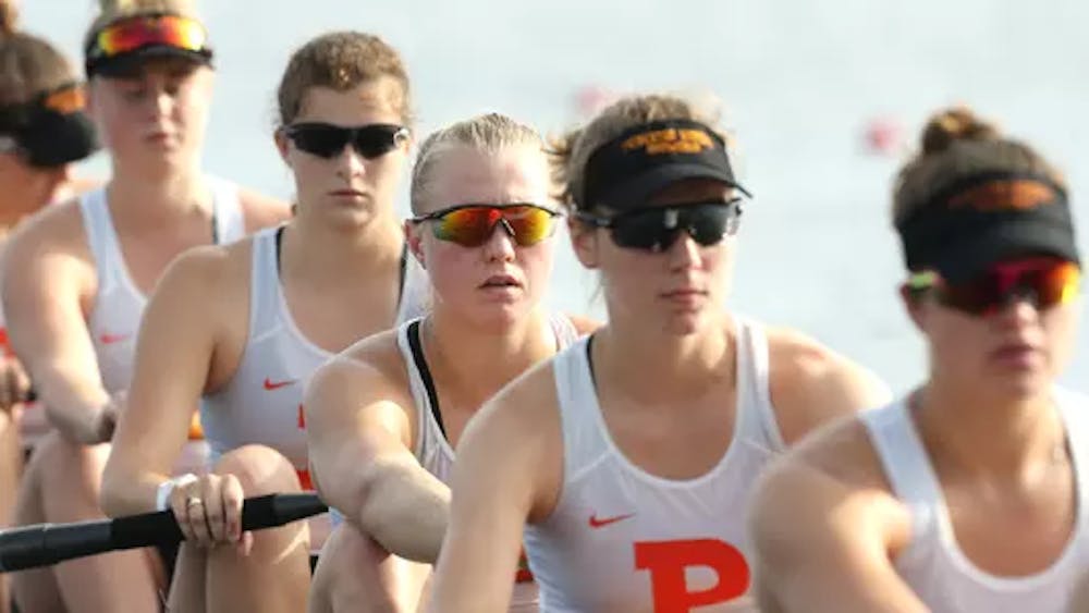 Five rowers wearing white tank tops with an orange "P" on them look forward and row oars.