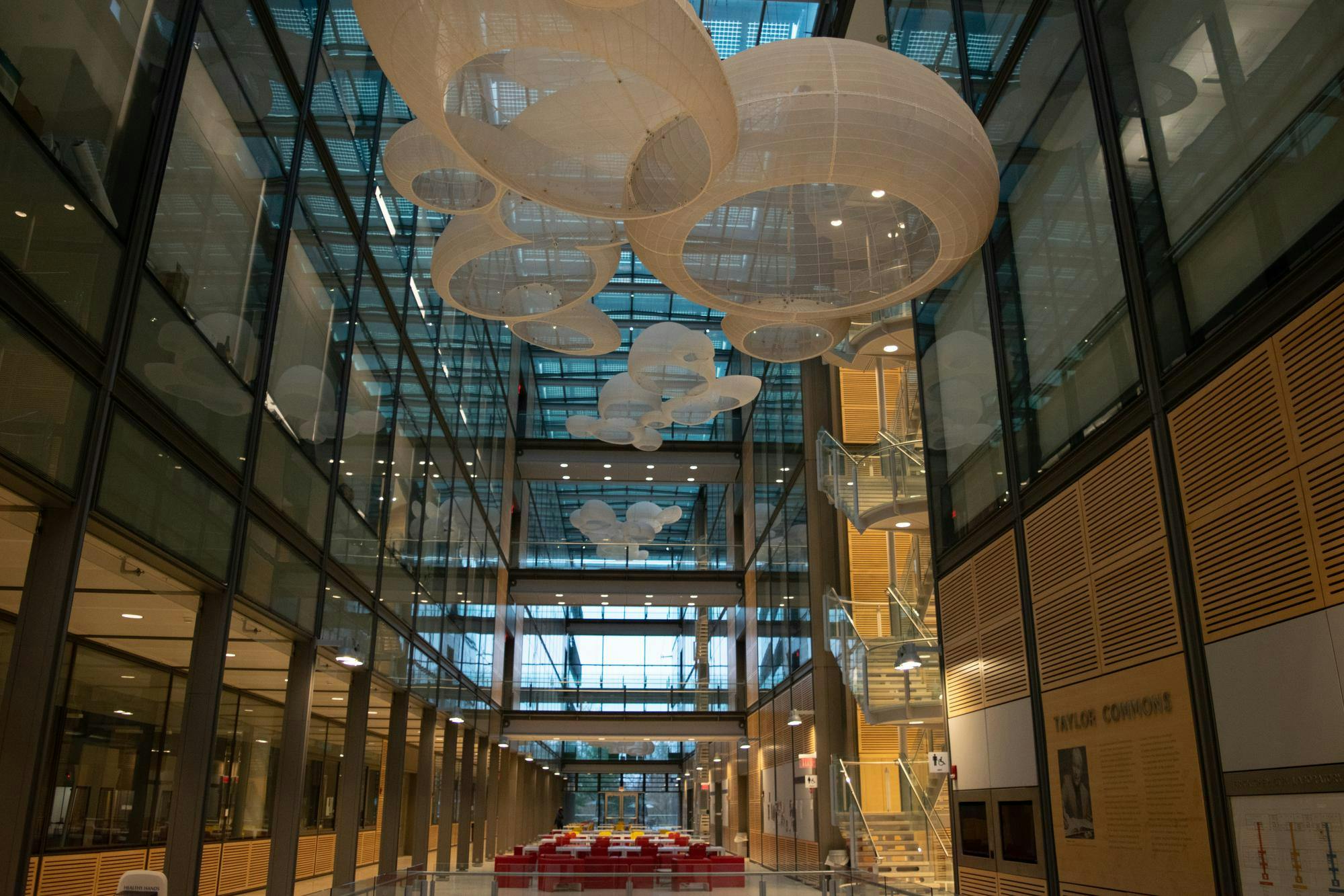 A large room with windows enveloping the interior, large white lanterns, and a spiraling staircase going up the right side.