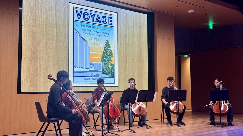 Six students sitting on chairs in a semi-circle, holding cellos, looking at music stands.