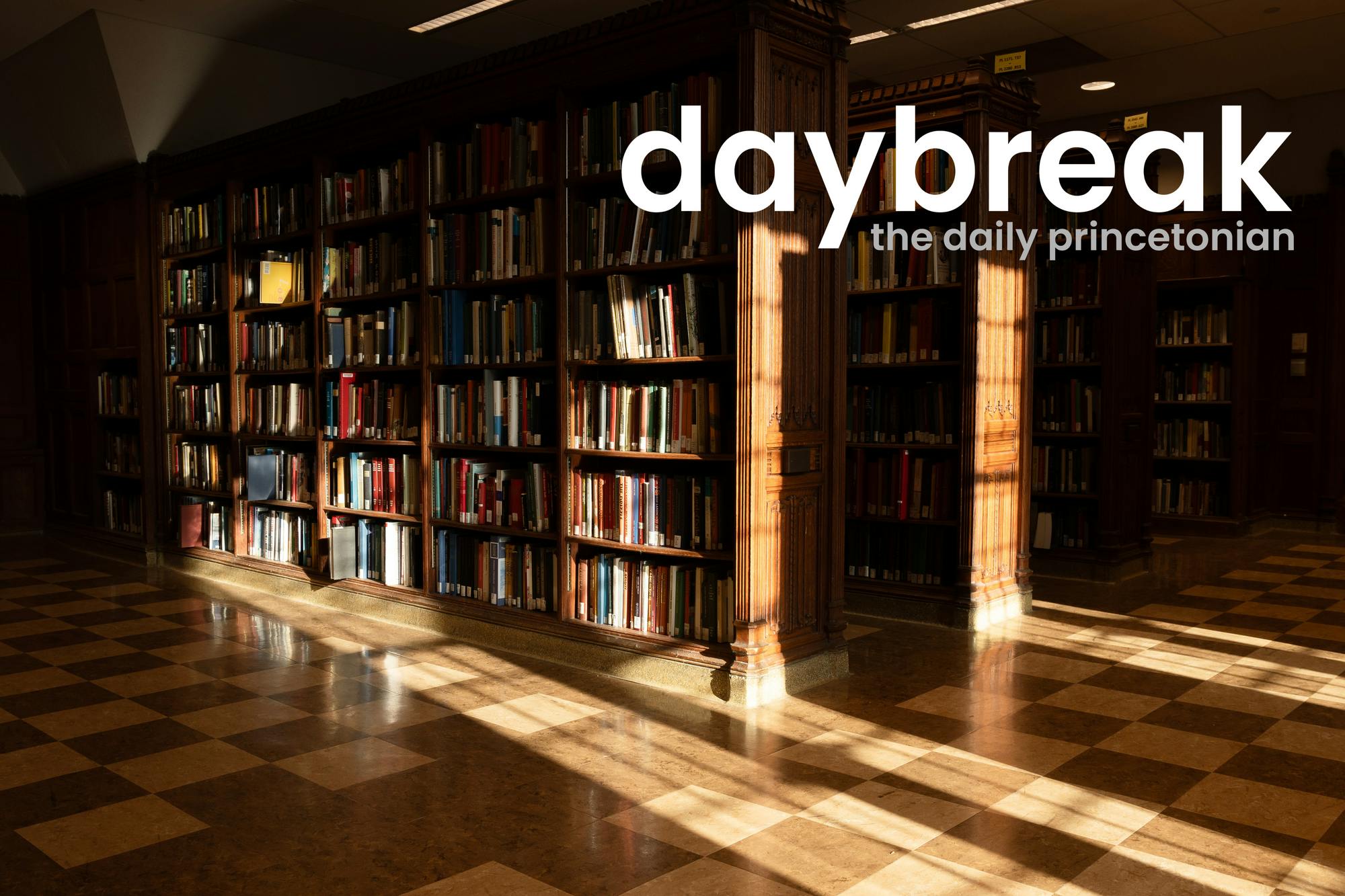 Photo of wooden library bookshelves, a checkerboard wooden floor, light from windows shines onto them. In the top left, a logo that says "daybreak: the daily princetonian"