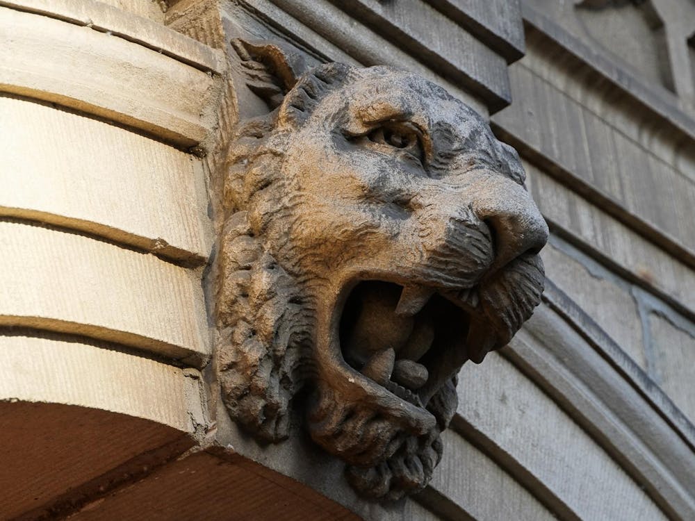 A stone lion gargoyle with an open mouth showing its teeth.