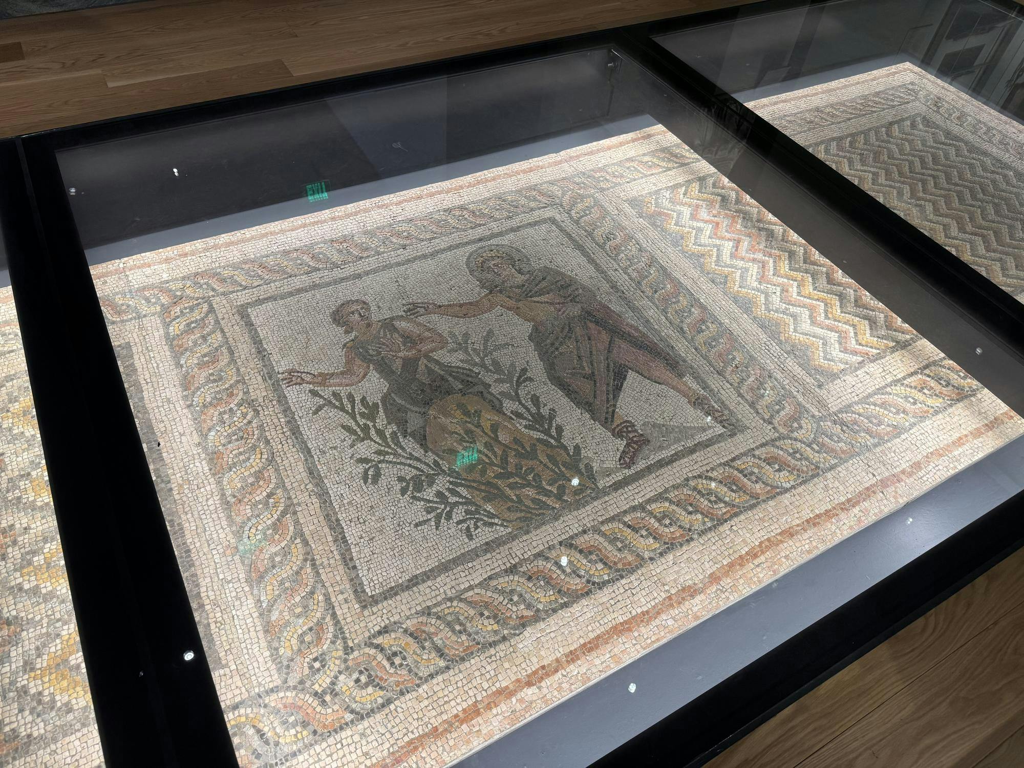 A mosaic depicting two people, under a layer of glass.