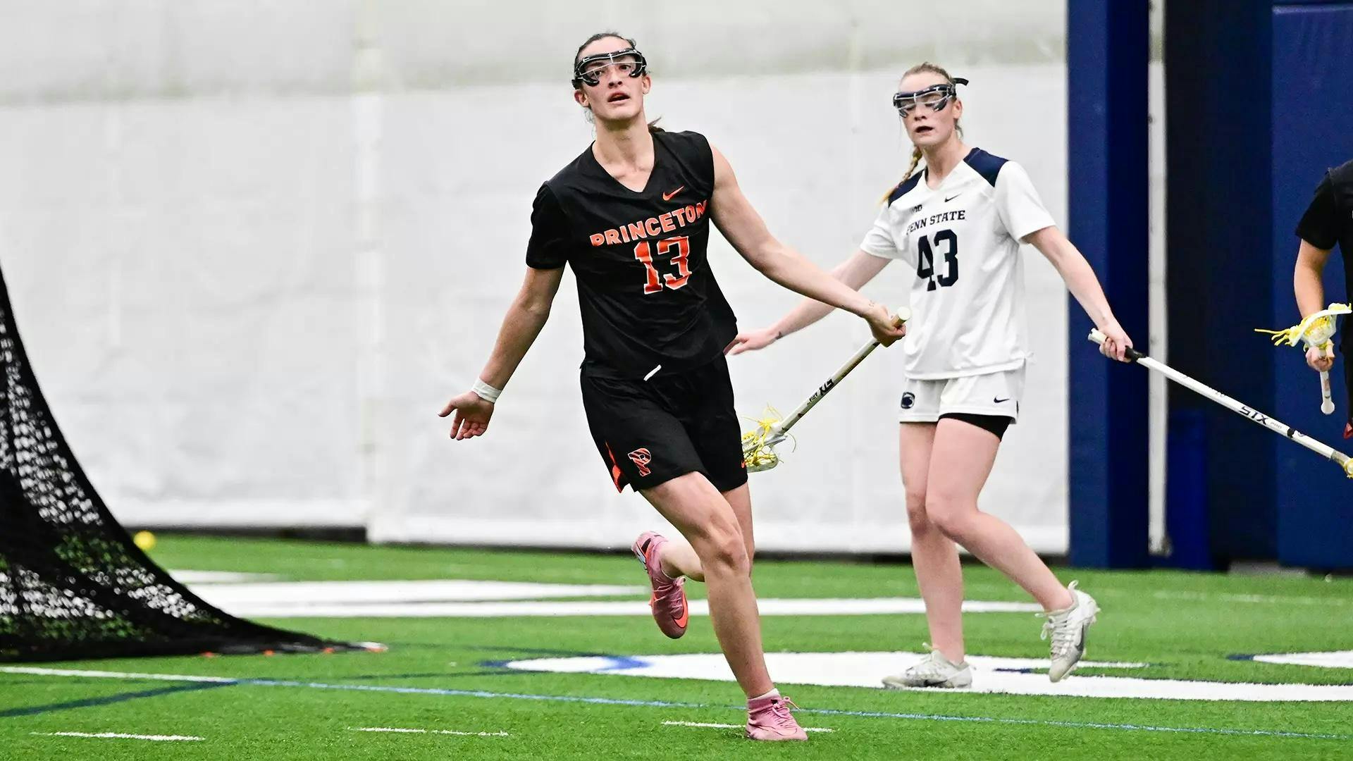 Princeton women’s lacrosse player in black jersey runs with arms outstretched.