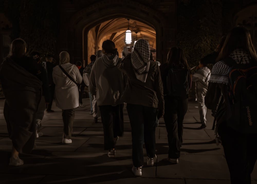 Multiple people walking in a dimly lit area in a crowd.