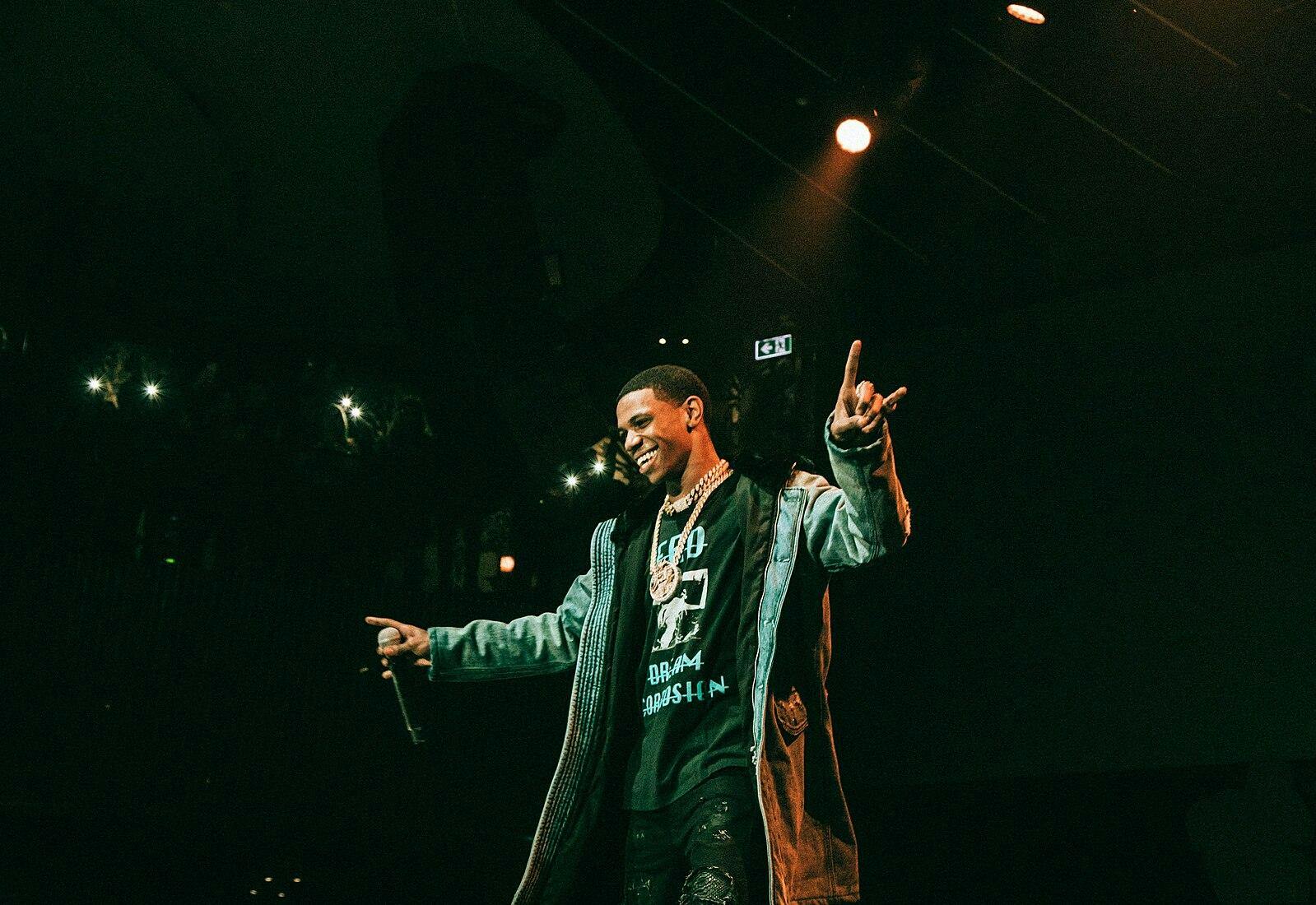 A man on a stage with a mic on his right hand performing 