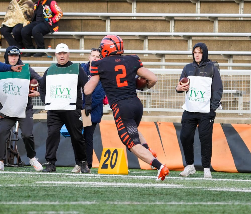 The back of a man in an orange and black uniform running with a football.