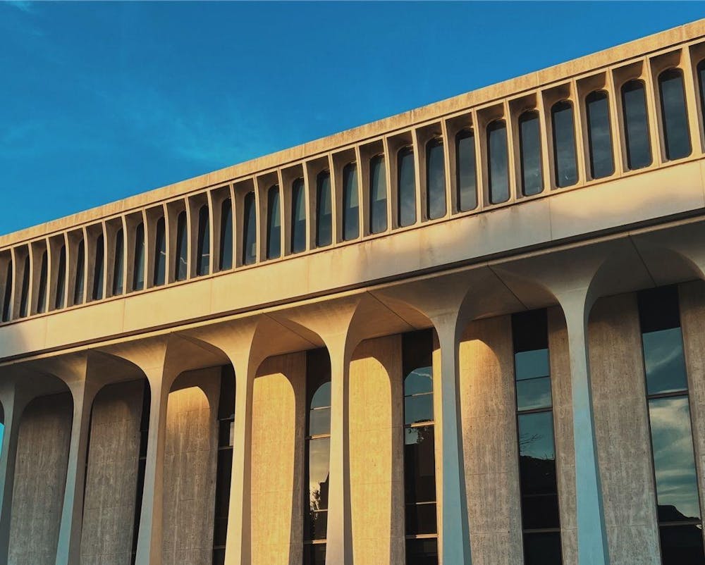 A white building with columns is lit by sunlight.