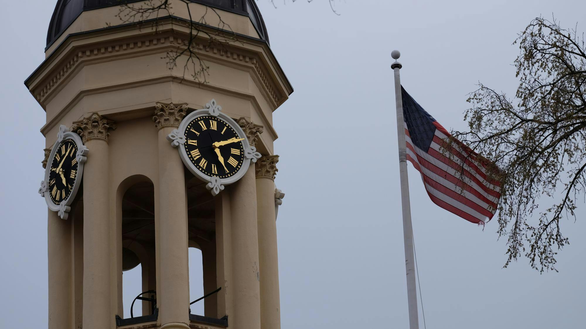 A clock tower on the left and an American flag on the right