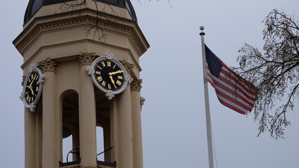 A clock tower on the left and an American flag on the right