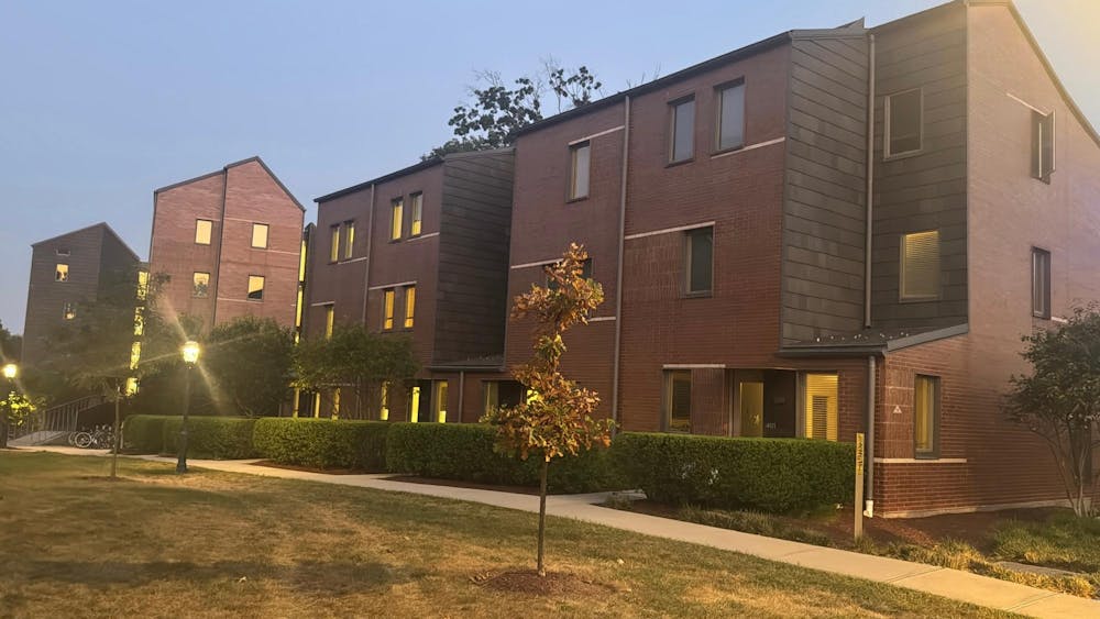 A few sparse trees in front of a row of red brick apartment buildings.