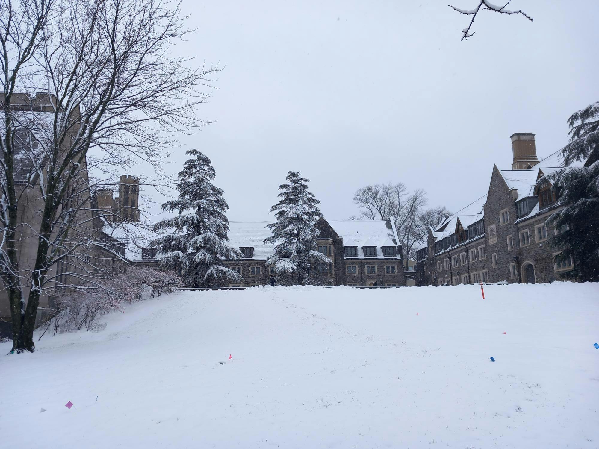 Snow covers a courtyard surrounded by large stone buildings. 