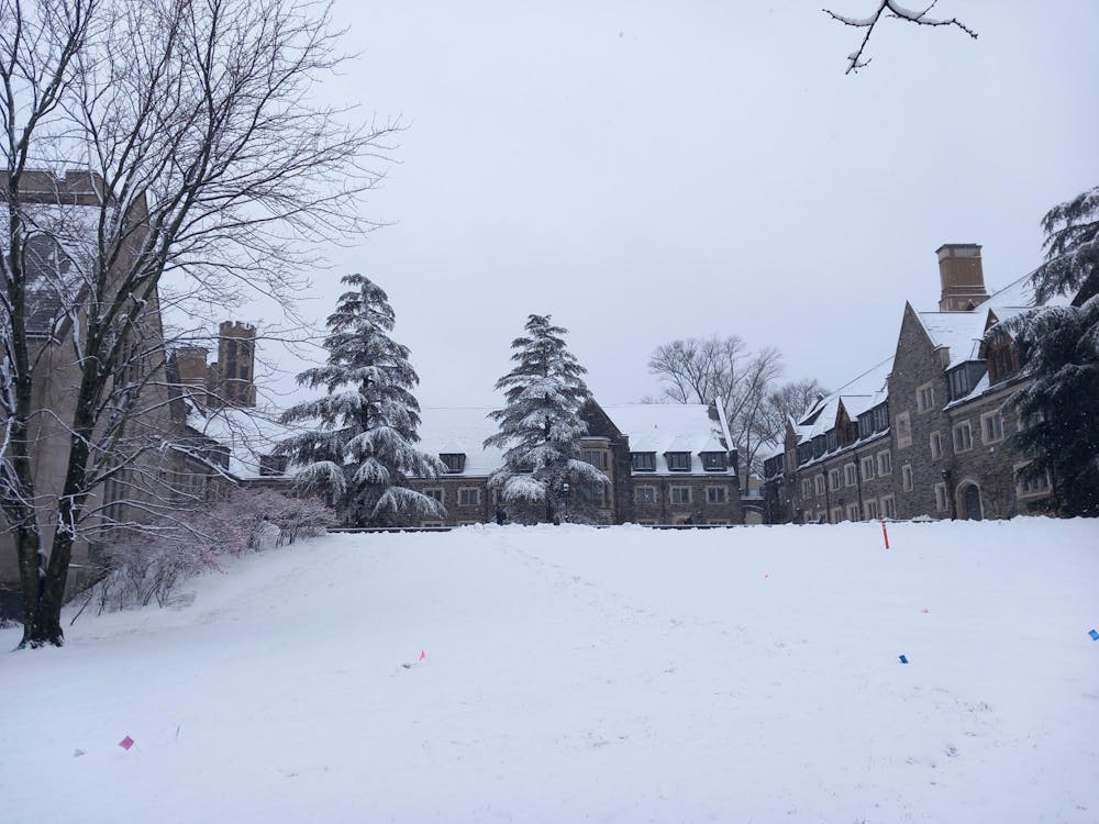 Snow covers a courtyard surrounded by large stone buildings. 