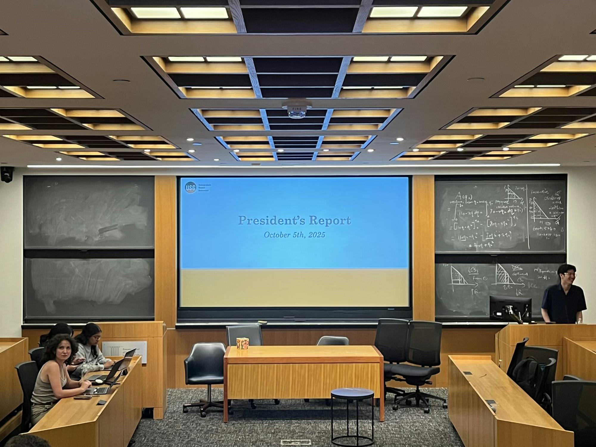 A photo of a powerpoint reading "President's Report" surrounded by chalkboard in a classroom in Robertson.  