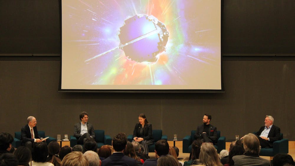 Five people in suits sit in front of a projector showing a space probe.