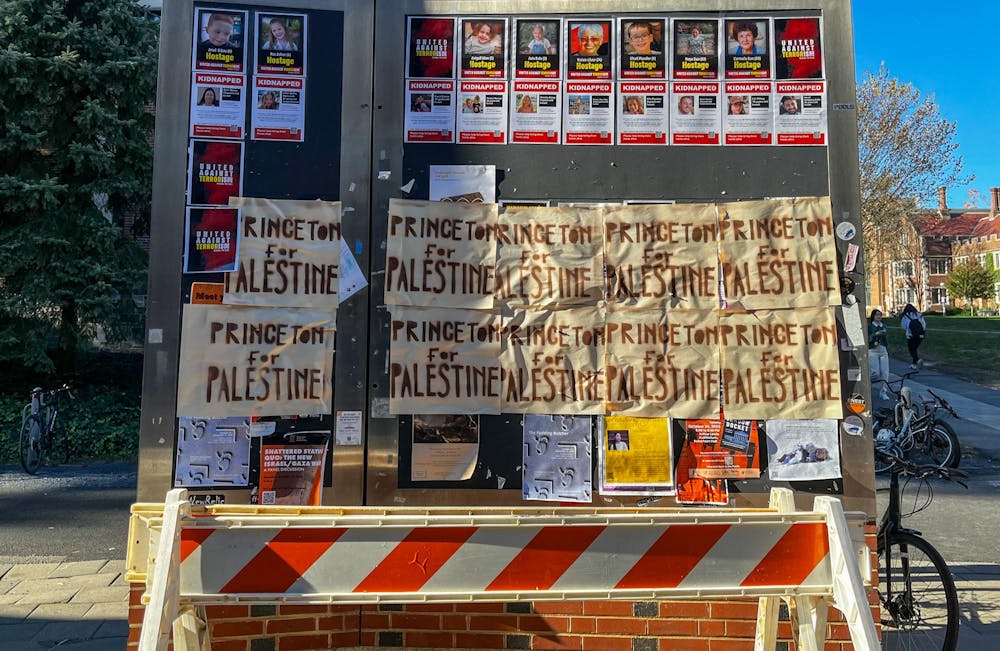 A display board outside of Frist Campus Center is pictured. On the bottom half of the board are two rows of handwritten "Princeton for Palestine" signs. The top right has printed signs for Israelis taken hostage by Hamas. 