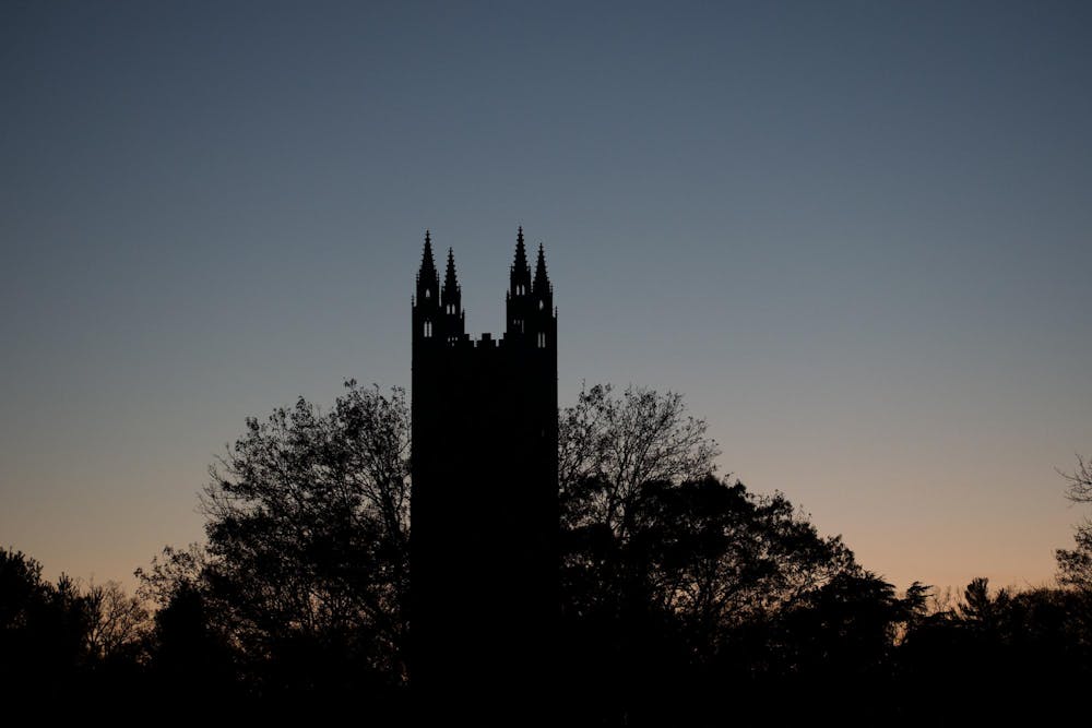 A tall building with four pointy spires with a sunset behind.