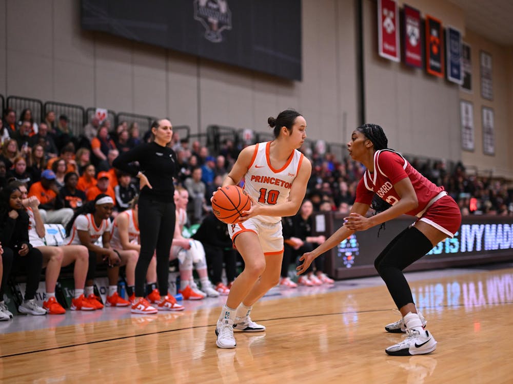 Two women are playing basketball on a court. Behind them is a crowd of people cheering.