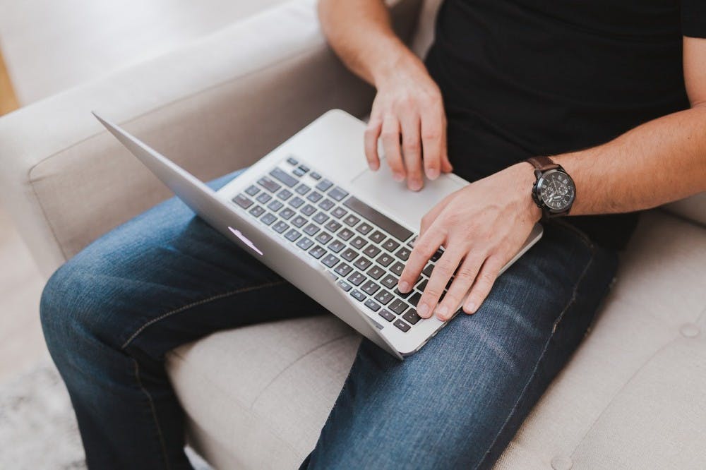 A man looking at his laptop while sitting on a couch, top view