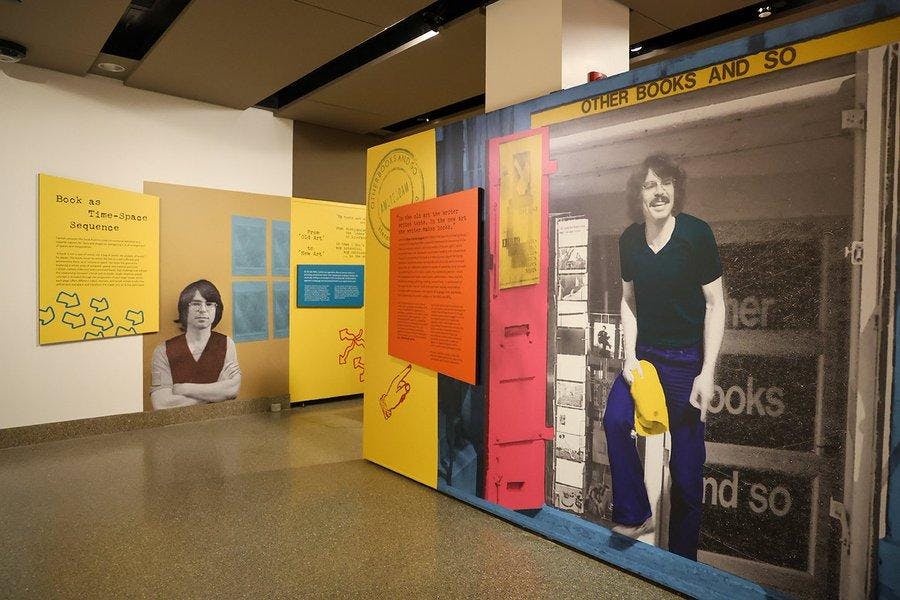 Paintings of a man on a wall. Black text on colorful backgrounds.