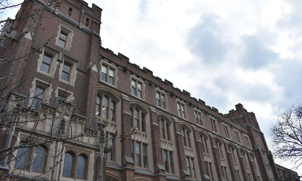 Un gran edificio de ladrillo con muchas ventanas ocupa toda la foto. El cielo al fondo es gris.