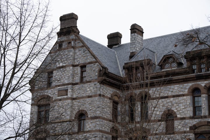 A building with a rocky exterior on a cloudy day, with bare trees in the foreground.